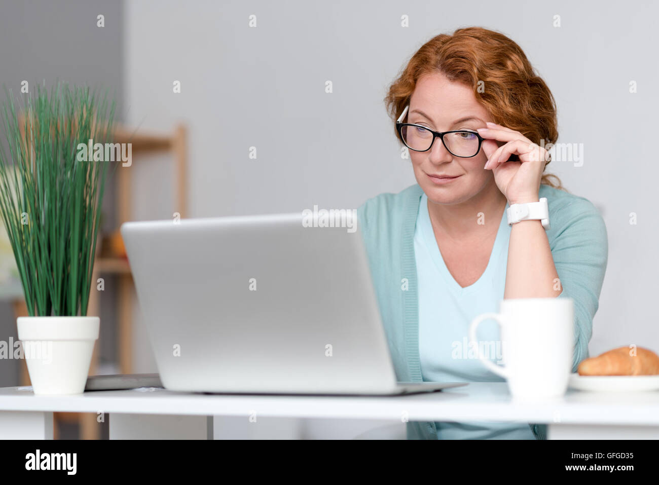 Pleasant concentrated woman sitting at the table Stock Photo - Alamy