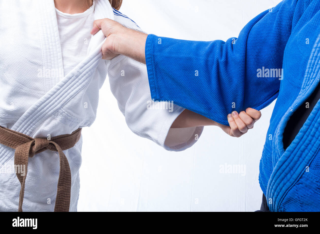 Judo Gripping between female judo brown belt and her sensei black belt isolated on white background Stock Photo