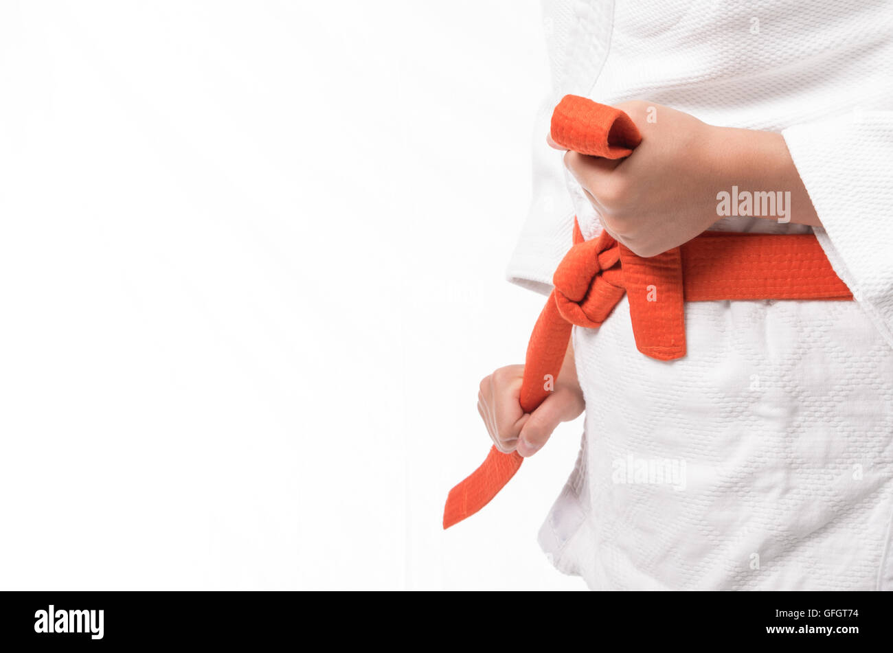 Female Hands Knotting orange martial belt in white judo uniform Stock