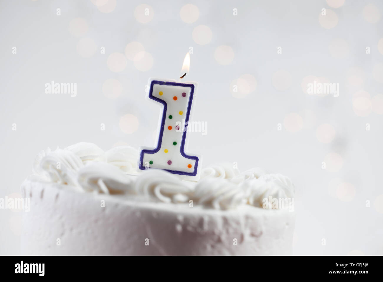 White iced cake with lit candles and a glowing background Stock Photo ...