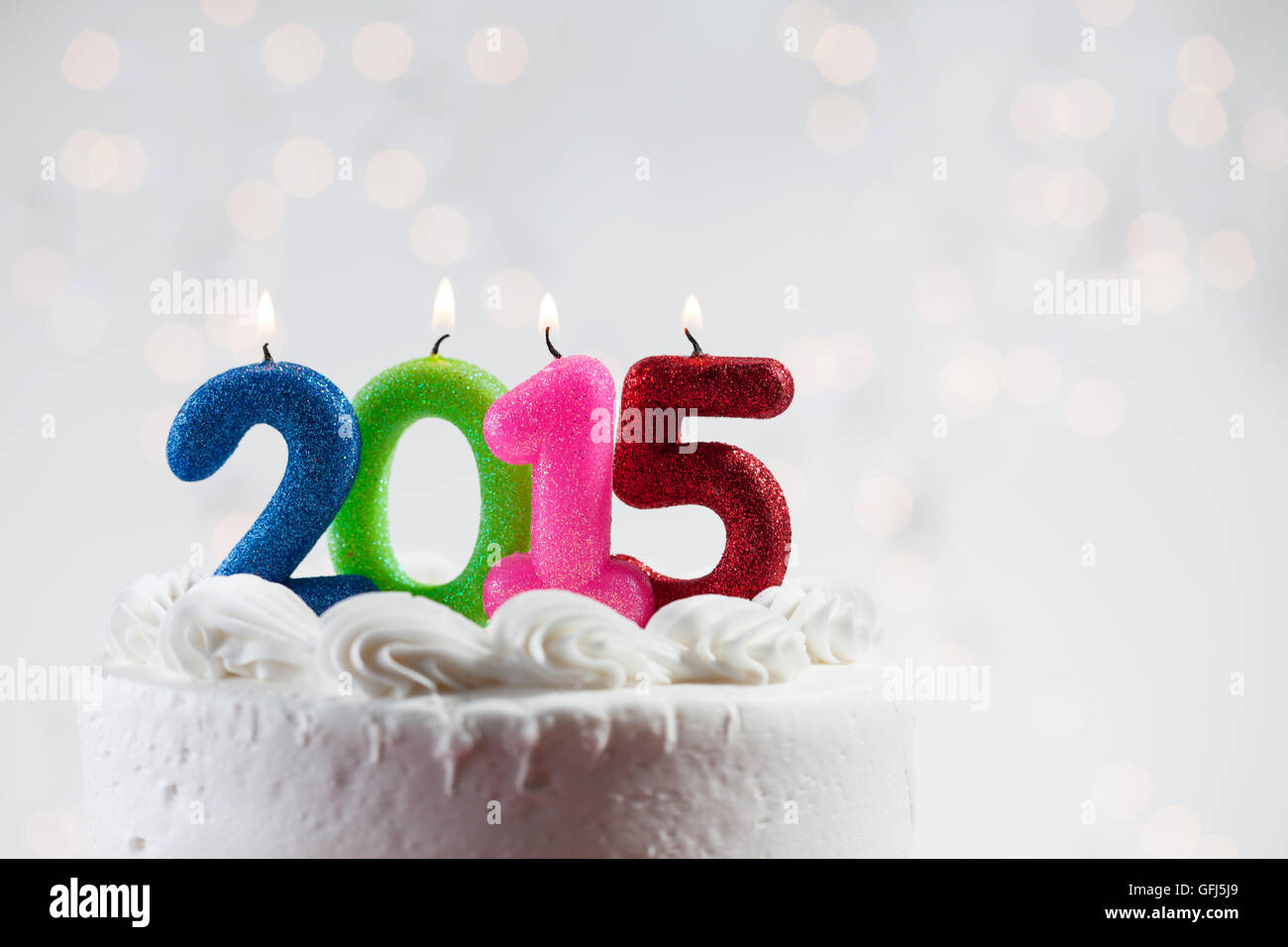 White iced cake with lit candles and a glowing background Stock Photo ...