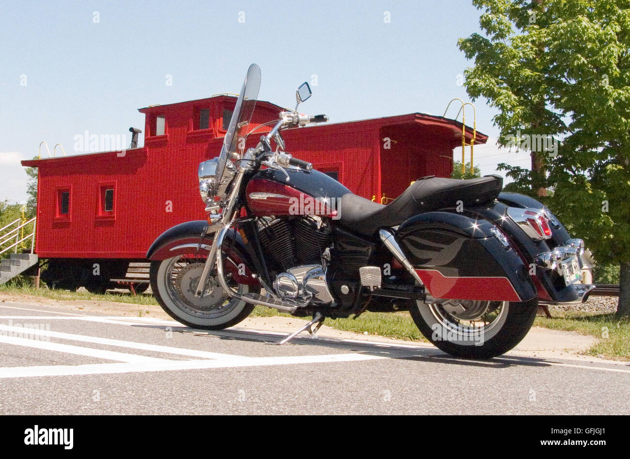 A beautiful cruiser-styled motorcycle is parked in front of a classic train caboose on display in Gainesville, Georgia. Stock Photo