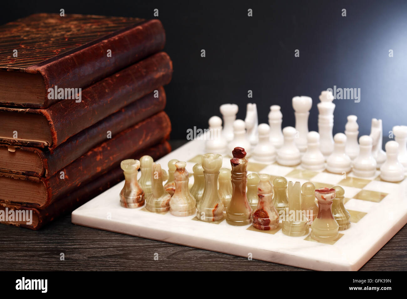 Set of chess pieces made from Onyx on board near books Stock Photo