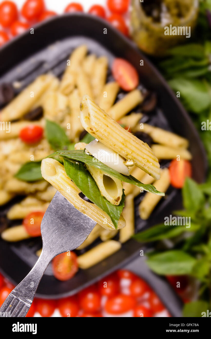 Penne pesto sauce pasta with grape tometo and black olive Stock Photo