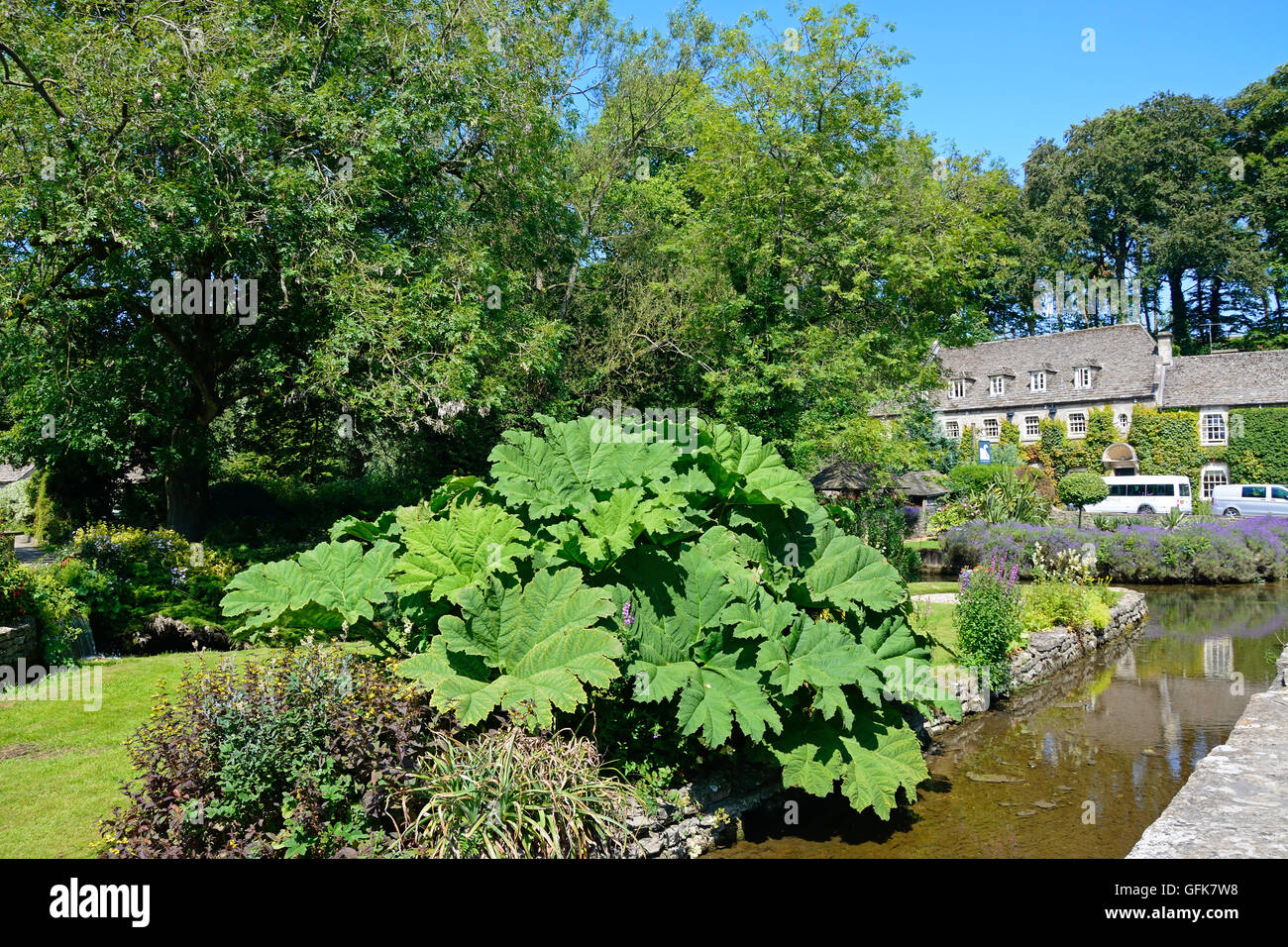View of the trout farm garden and River Coln with The Swan Hotel to the rear, Bibury, Cotswolds, Gloucestershire, England, UK. Stock Photo