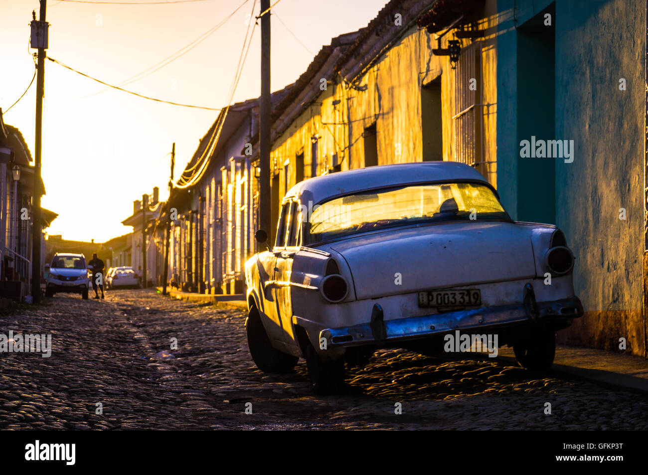 Sunset light shining on street with a white oldtimer in Trinidad, Cuba Stock Photo