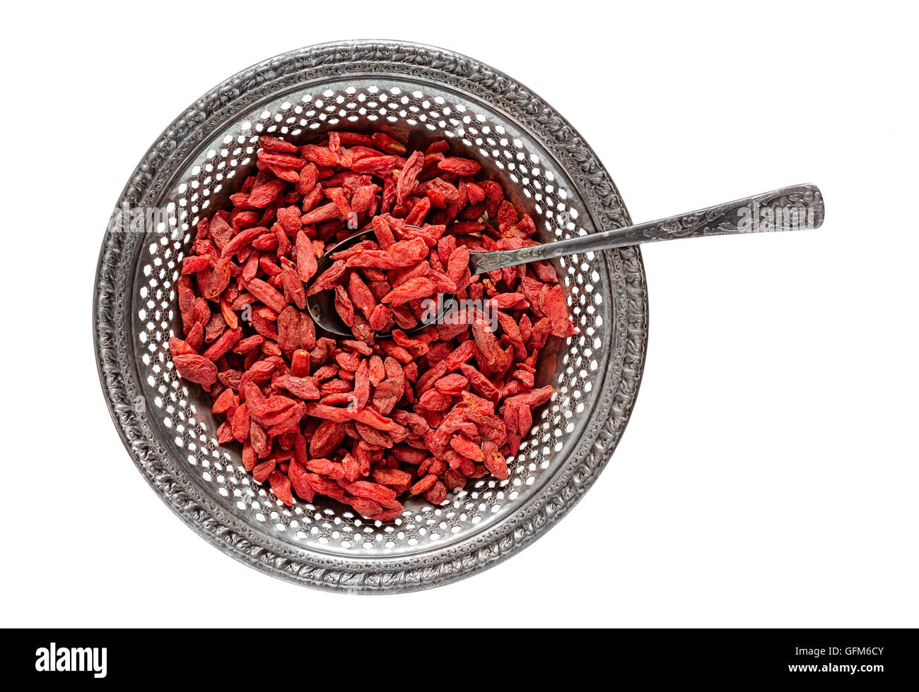 Antique metal bowl of raw dried goji berries with vintage teaspooned inside isolated on white Stock Photo