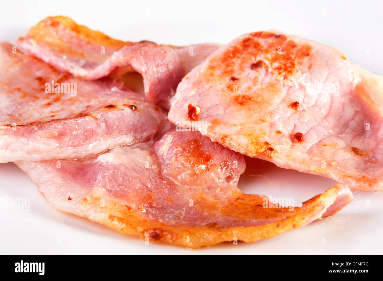 Fried bacon slices on a white plate. SDOF Stock Photo