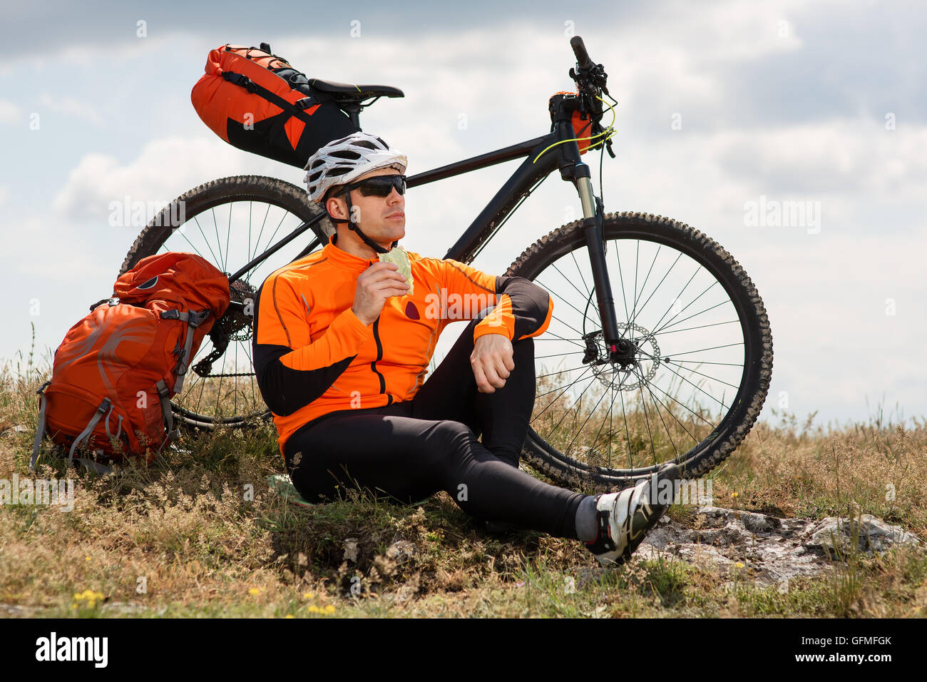 Active man sitting on bike and eating sandwich Stock Photo Alamy