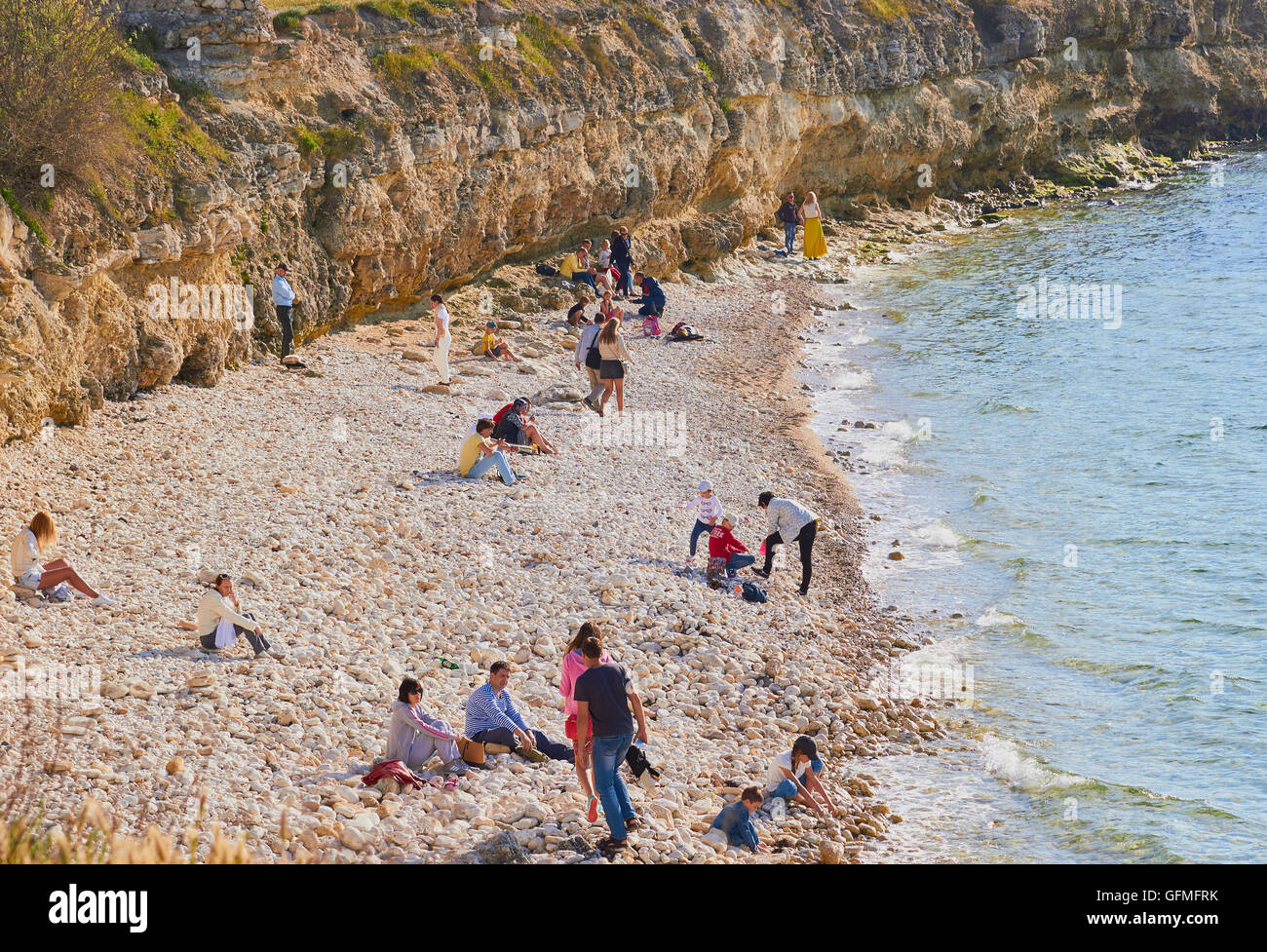 Tourists on pebble beach at Chersonesus on the Black Sea coast, Crimea Stock Photo