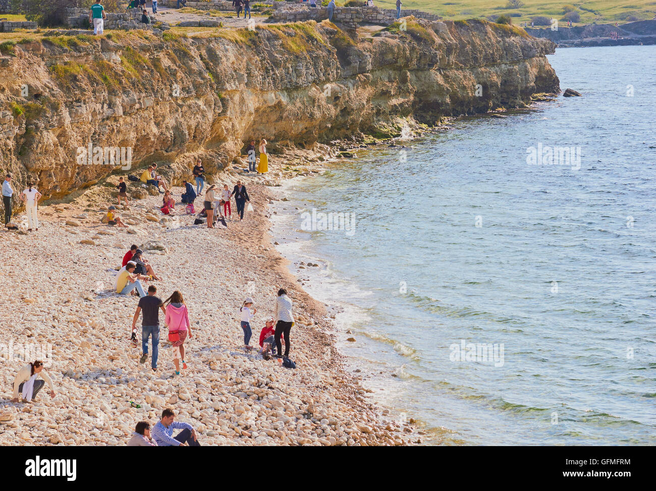 Tourists on pebble beach at Chersonesus on the Black Sea coast, Crimea Stock Photo