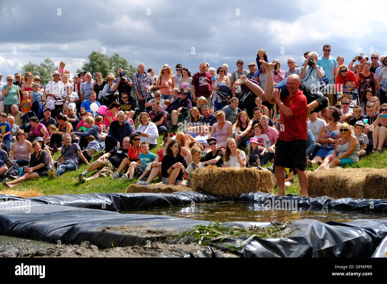 Lowland Games, Thorney, Somerset, UK, 31 July 2016: Competitors take part in the annual Lowland Games Wife Carrying race in Somerset. Hundreds turned out in the heat to watch the Lowland Games which includes such events as a Raft Race, Hay Bale Racing , River its a Knock Out, Mud Wrestling, and Chunder Challenge. The games, originally started in 1984, are held annually in the Lowland village of Thorney which became flooded for the first time in centuries during the Somerset floods in January 2014. Credit:  Tom Corban/Alamy Live News Stock Photo