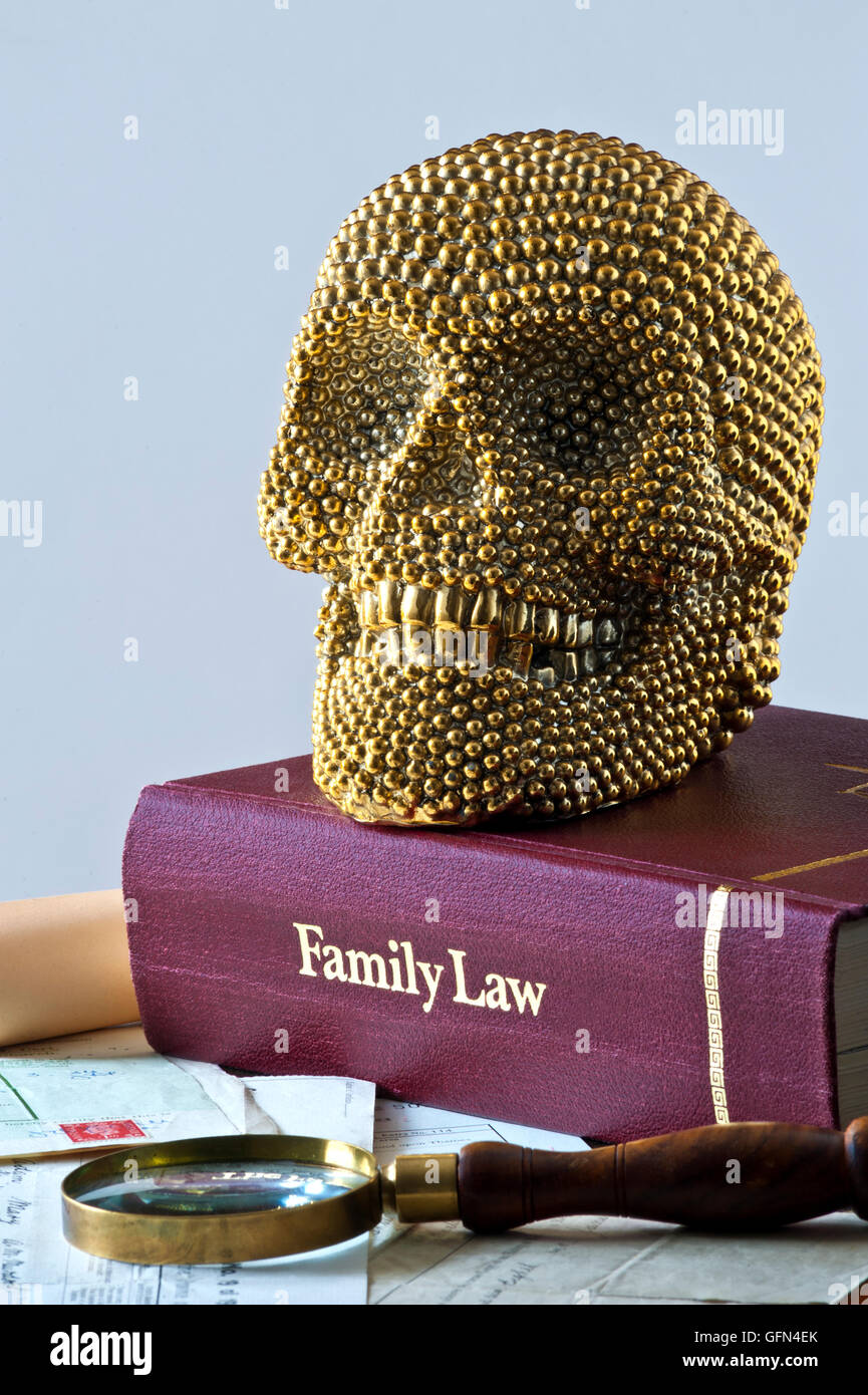Concept image of smiling gold themed human skull on Family Law book with various official legal documents and magnifying glass Stock Photo