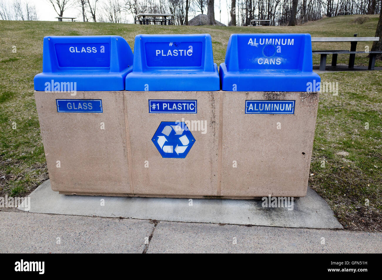 Three individual recycling bins for glass, plastic and aluminum cans at
