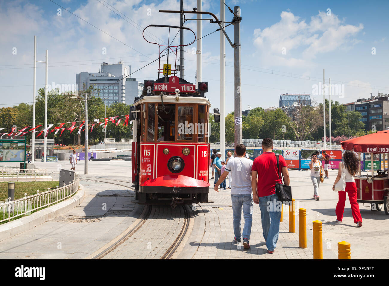 Istanbul, Turkey - July 1, 2016: Vintage red tram goes on Taksim square in Istanbul, ordinary people walk nearby Stock Photo