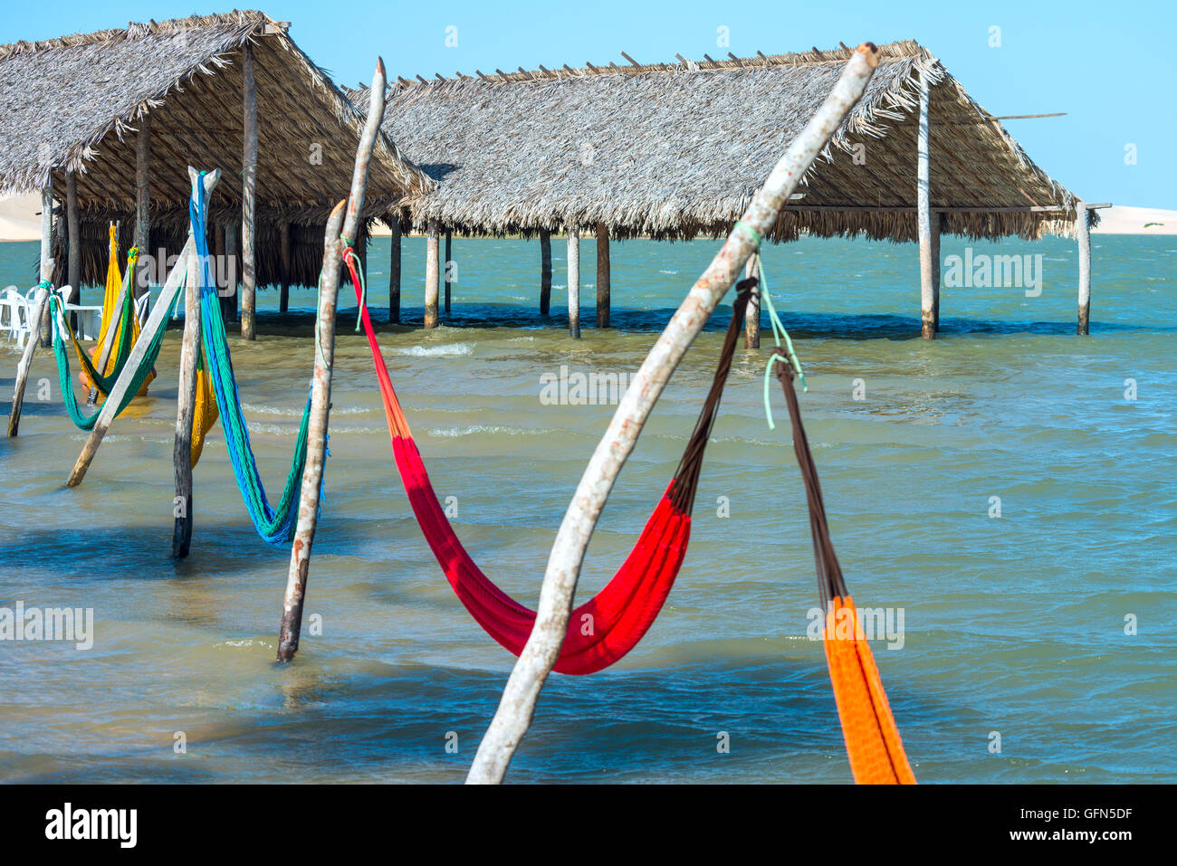 Hammocks and beach chairs under the shade of a palapa sun roof umbrella in Jericoacoara, Brazil Stock Photo
