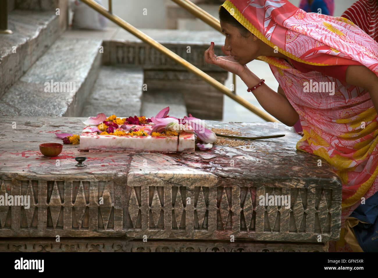 A Hindu woman marks her forhead with a Tilaka or tika in Hindi at the Jagdis Temple in Udaipur, Rajistan, India. Stock Photo