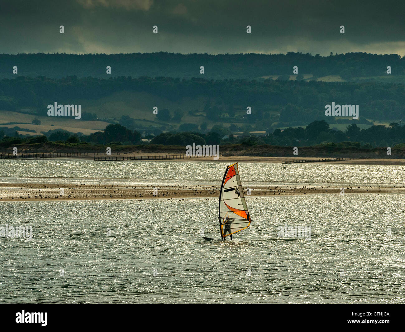 Windsurfing along the beautiful Jurassic seaside coast around the mouth of the River Exe estuary, with blue sea and sky. Stock Photo