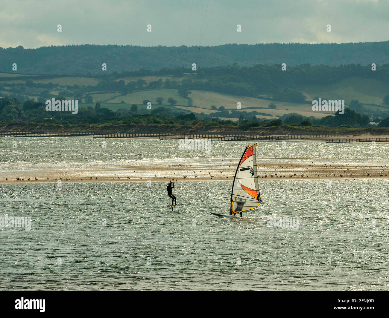 Kite & Windsurfing along the beautiful Jurassic seaside coast around the mouth of the River Exe estuary, with blue sea and sky. Stock Photo
