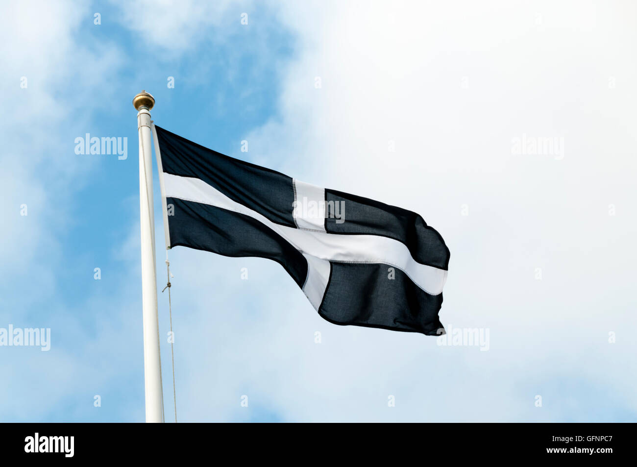 The Cornish flag flying in front of a blue sky. Stock Photo