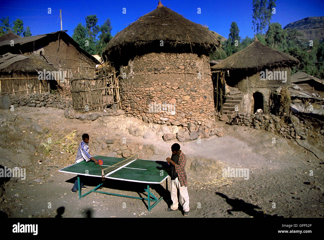 Two boys playing table tennis in the front yard of a 100 year old