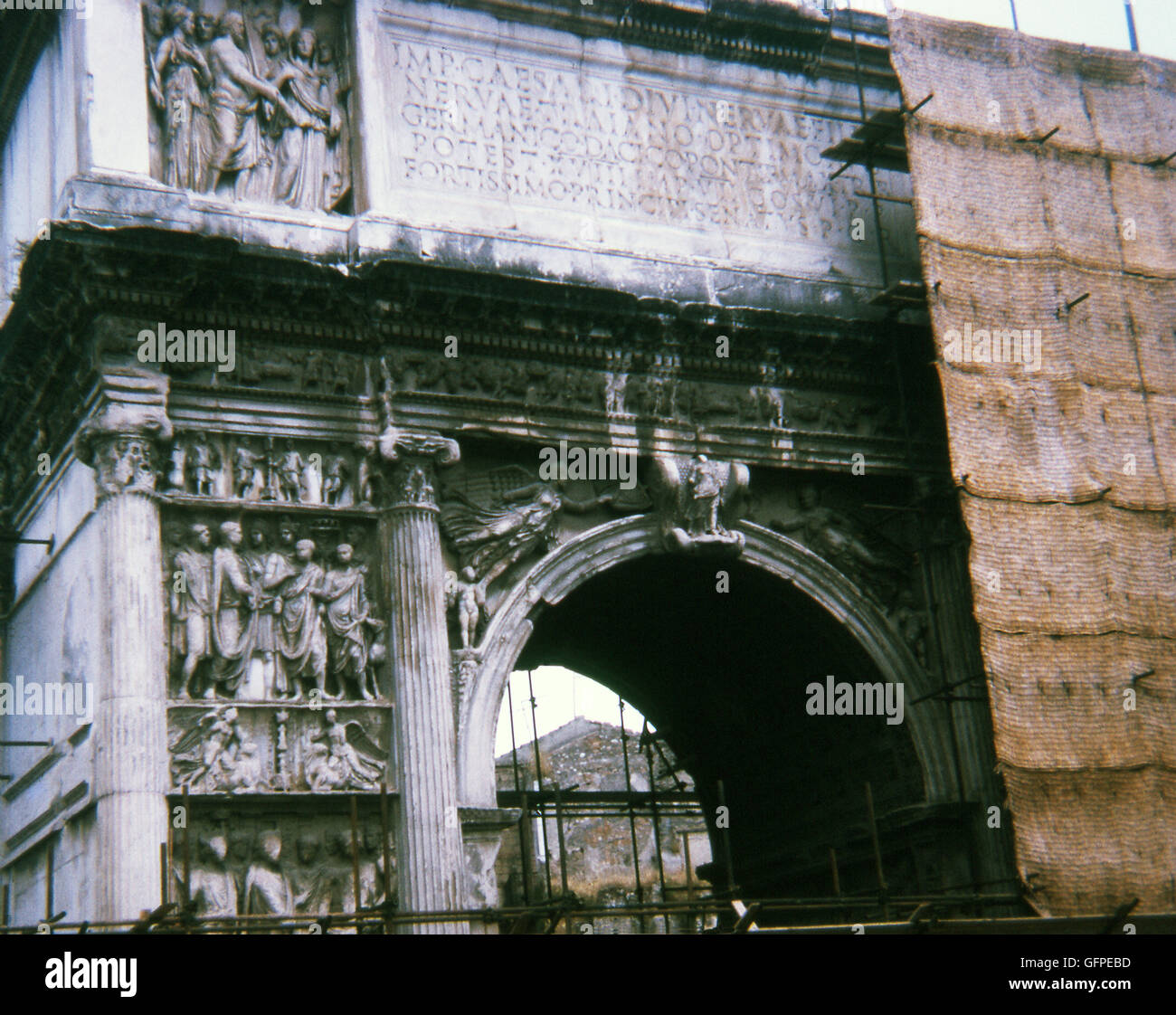 This photo, taken in 1970, shows the Arch of Trajan at Benevento (Beneventum) in southern Italy when it was under construction. The arch straddles the Via Appia (Appian Way) at its entry point to Benevento. The arch was built in A.D. 114. The arch was built to commemorate the completion of the Via Traiana, which offered a faster route to Rome than the Via Appia. The reliefs on the arch glorify Trajan and his accomplishments, especially his conquest of new lands. A key feature of the reliefs is the numerous young people depicted, including young people receiving the alimenta, the public welfare Stock Photo