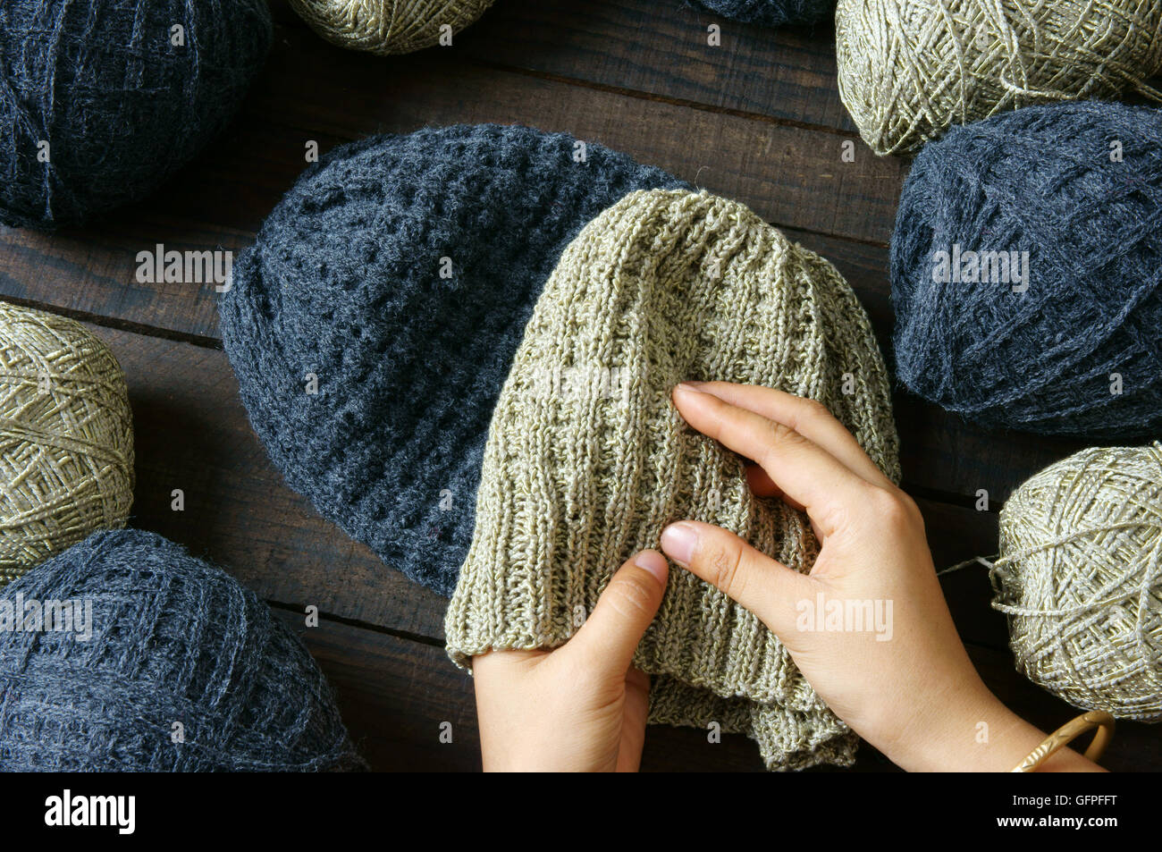 Handmade gift for couple on wintertime, woollen hat in black and beige color, woman hand knitting from ball of yarn Stock Photo
