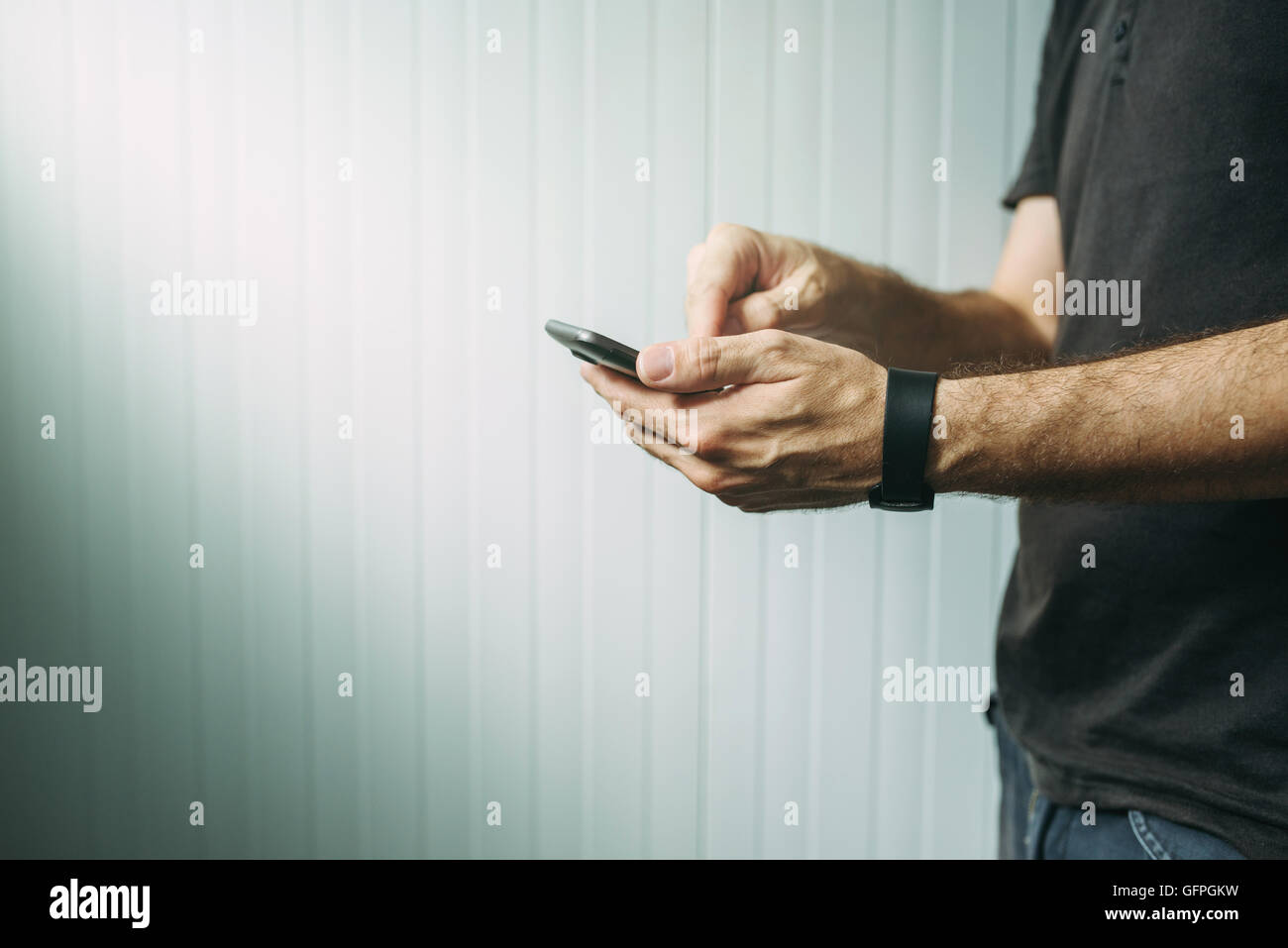 Casual man using smart phone to send text message, male hands holding mobile telephone device, selective focus Stock Photo