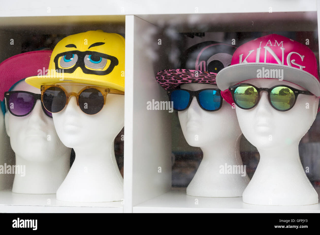 Mannequin heads wearing caps and sunglasses on display in window of