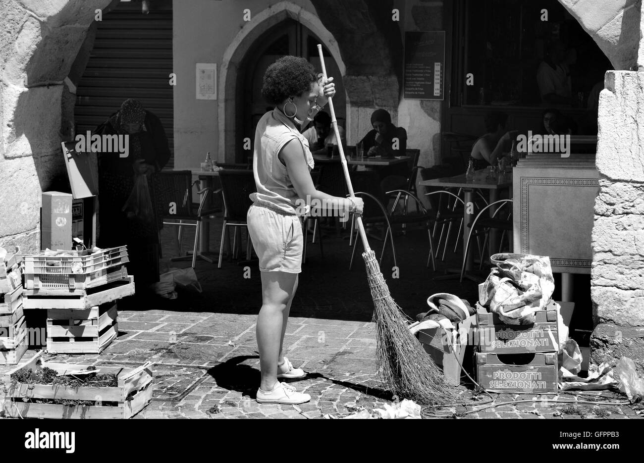 Woman market stall holder sweeping cleaning street clearing waste rubbish at Annecy in France Stock Photo