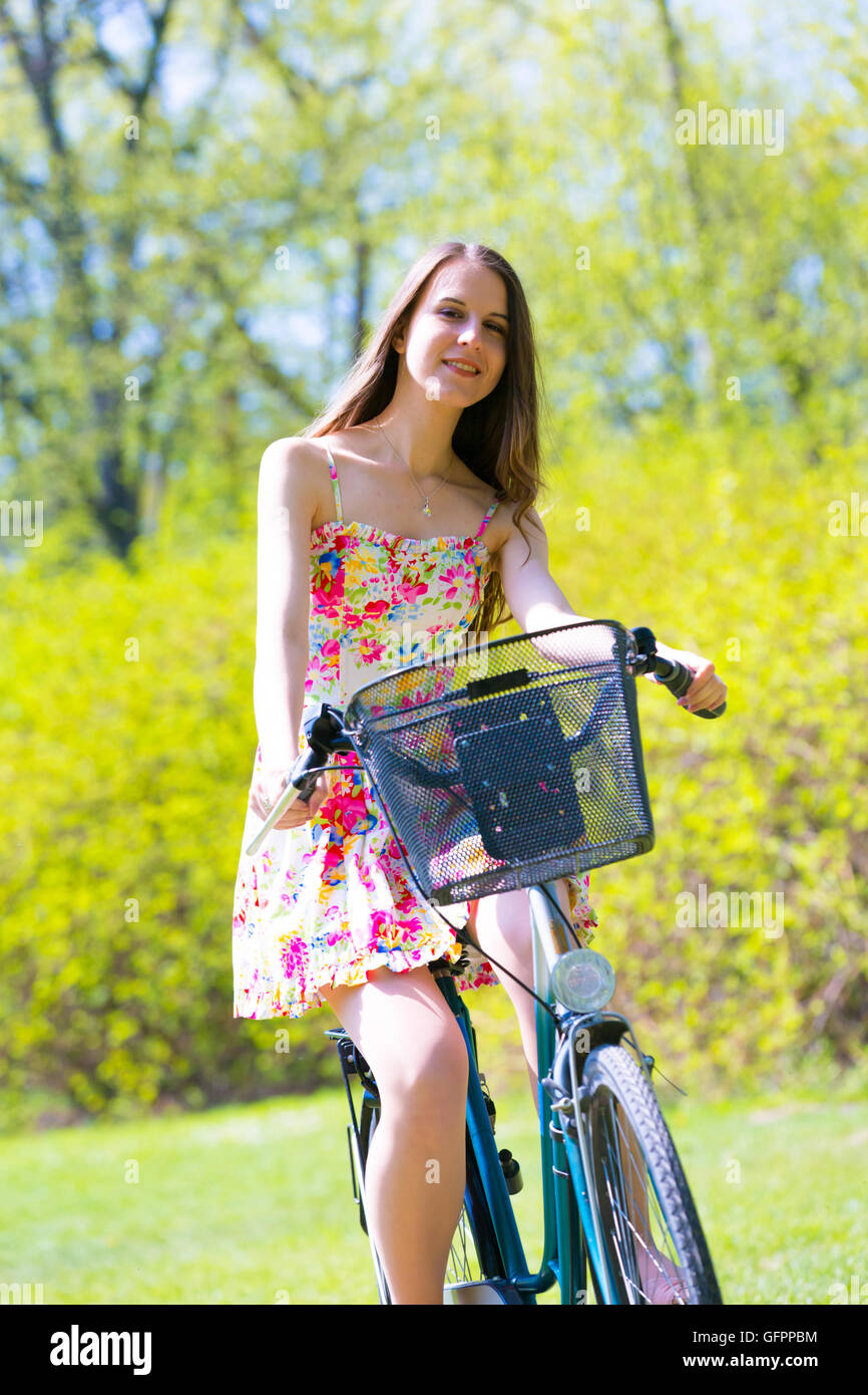 A girl wearing color dress with bike in summer park Stock Photo