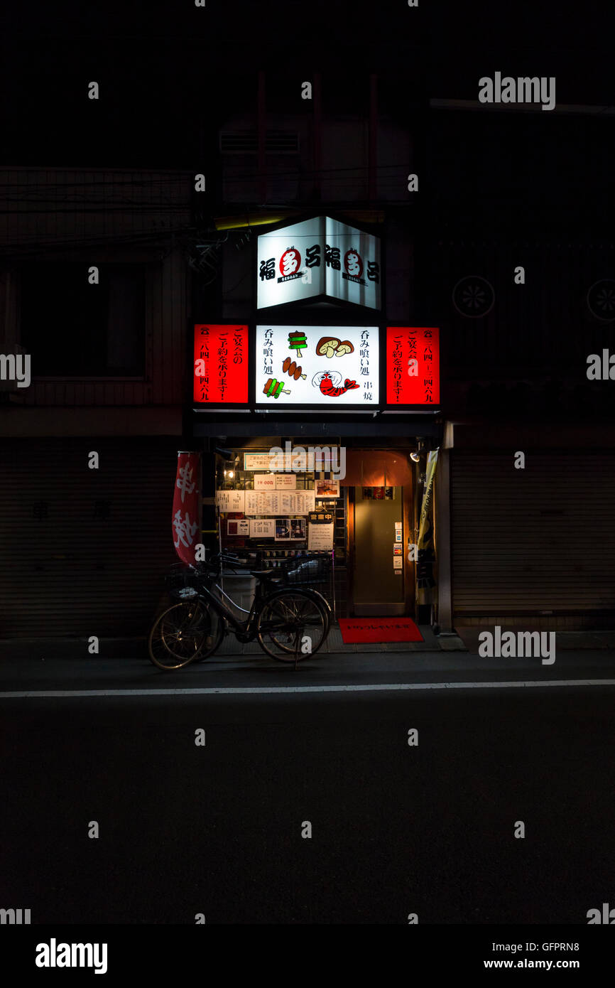 Single small restaurant with red illuminated advertising and bicycles close to Ueno train station in Tokyo, Japan Stock Photo