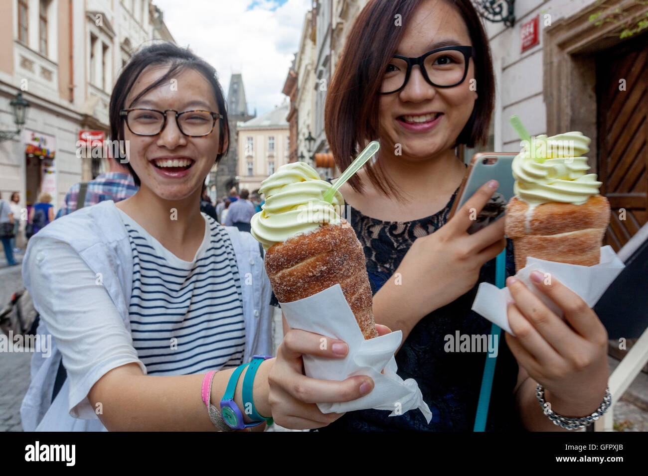 Trdelnik with ice cream, traditional Czech sweets for summer days, Celetna street Old Town, Young Asian women tourists Prague Tourism Czech Republic Stock Photo