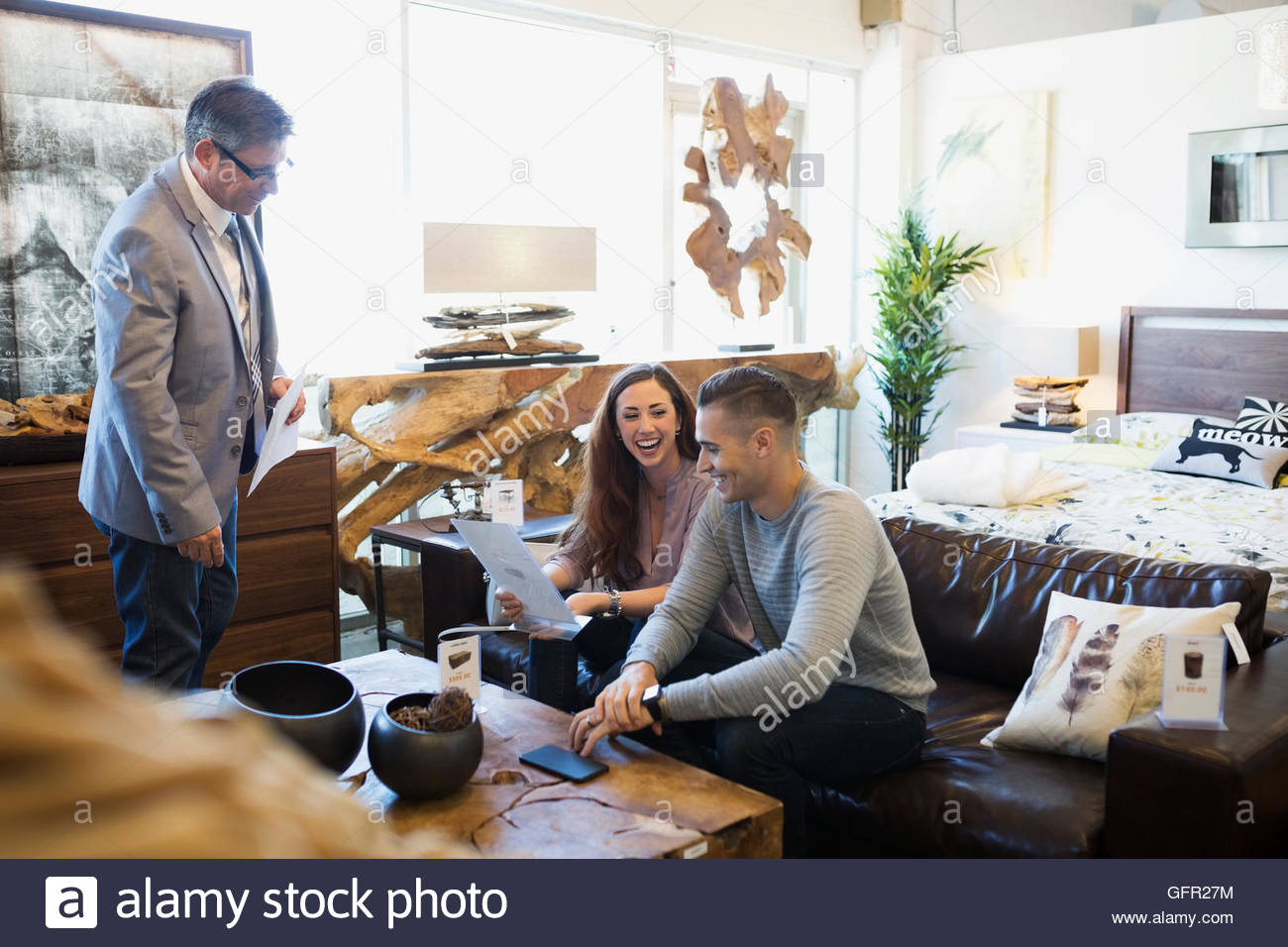 Salesman helping couple in home furnishings store Stock Photo