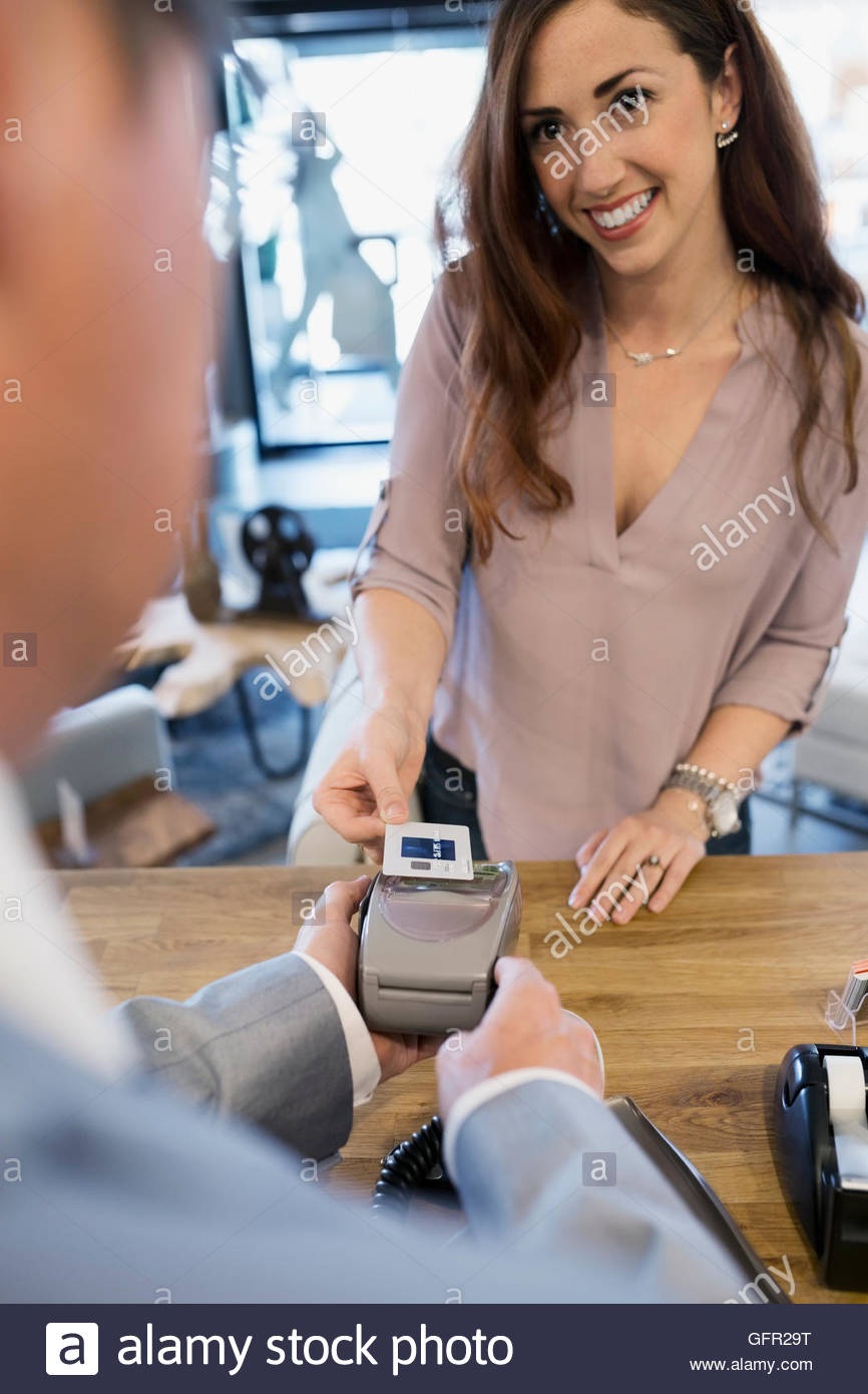 Woman paying using credit card reader in home furnishings store Stock