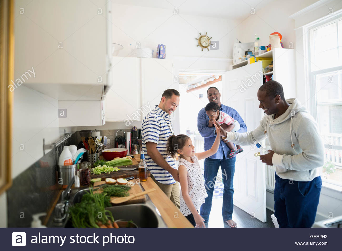 Fathers and children high fiving in kitchen Stock Photo