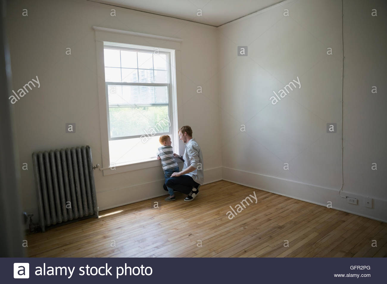 Father and son at window in empty new house Stock Photo