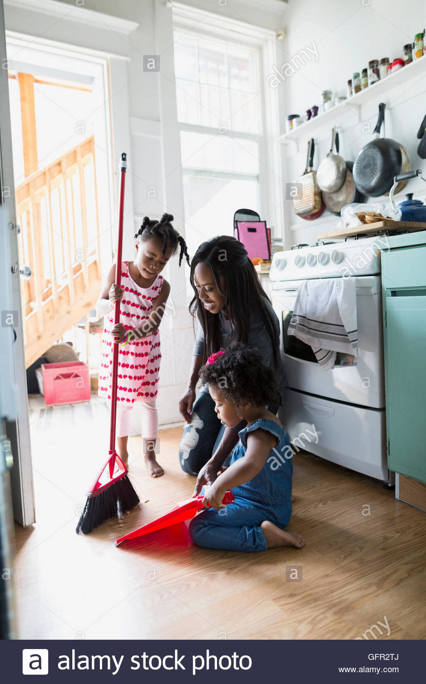 Daughters helping mother sweep kitchen floor Stock Photo Alamy