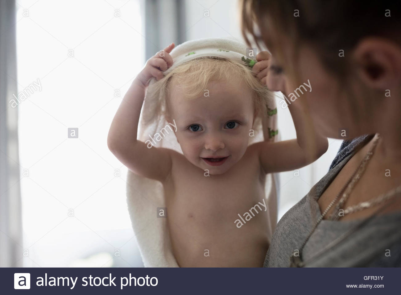 Portrait mother holding baby daughter with towel over head Stock Photo