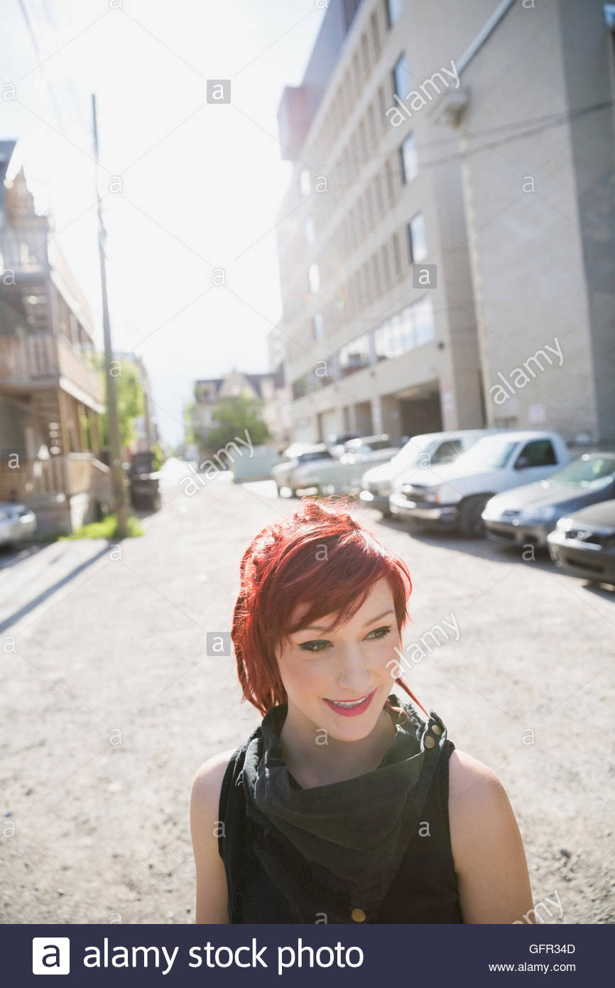 Cool woman with red hair on sunny urban street Stock Photo