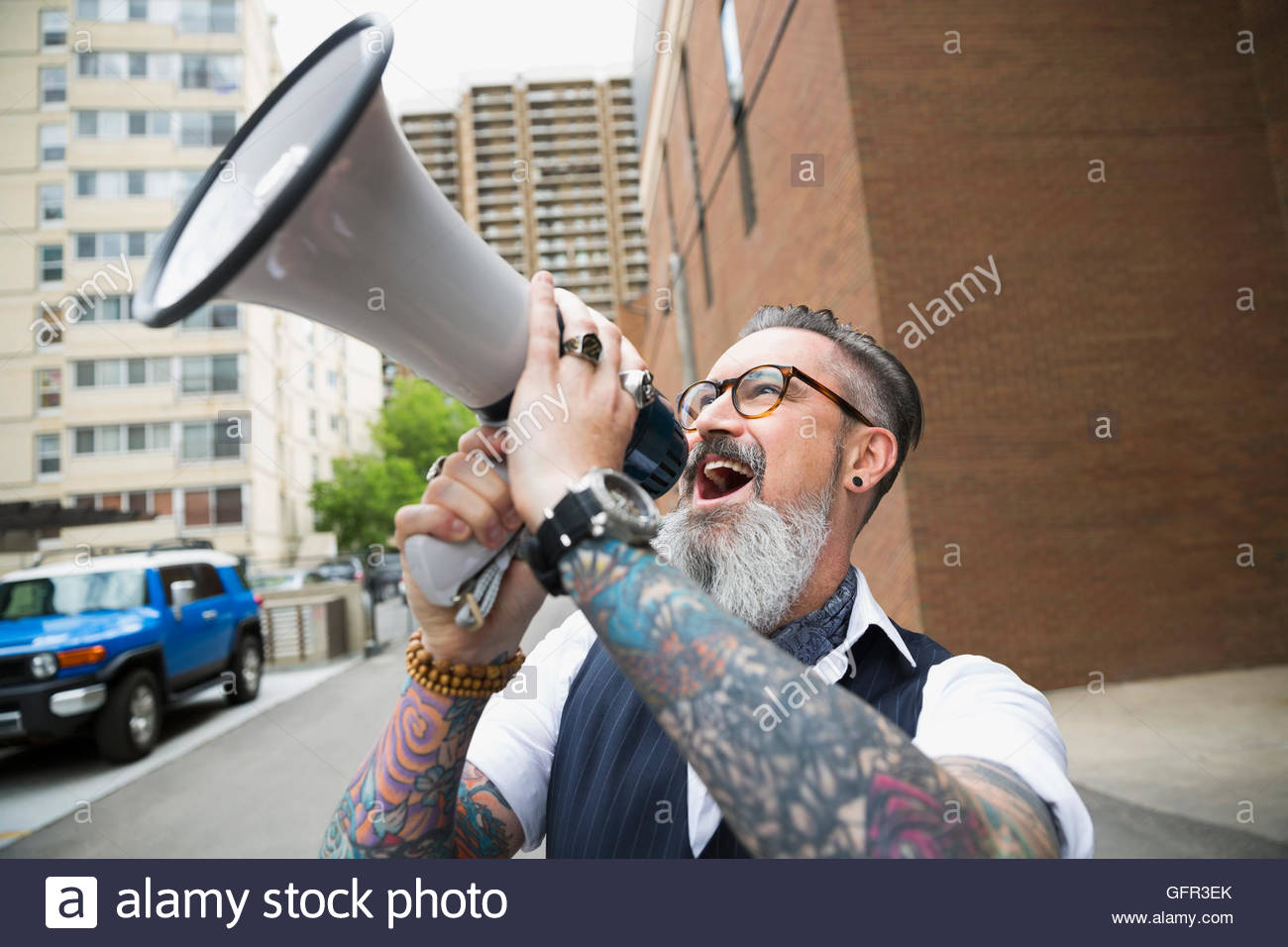 Hipster with beard and tattoos using megaphone in city Stock Photo Alamy