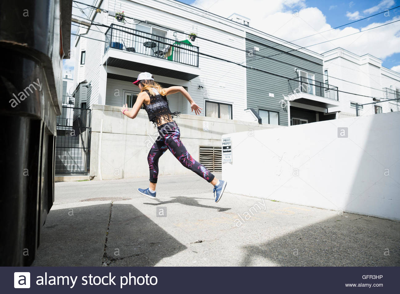 Young woman running in sunny urban alley Stock Photo Alamy
