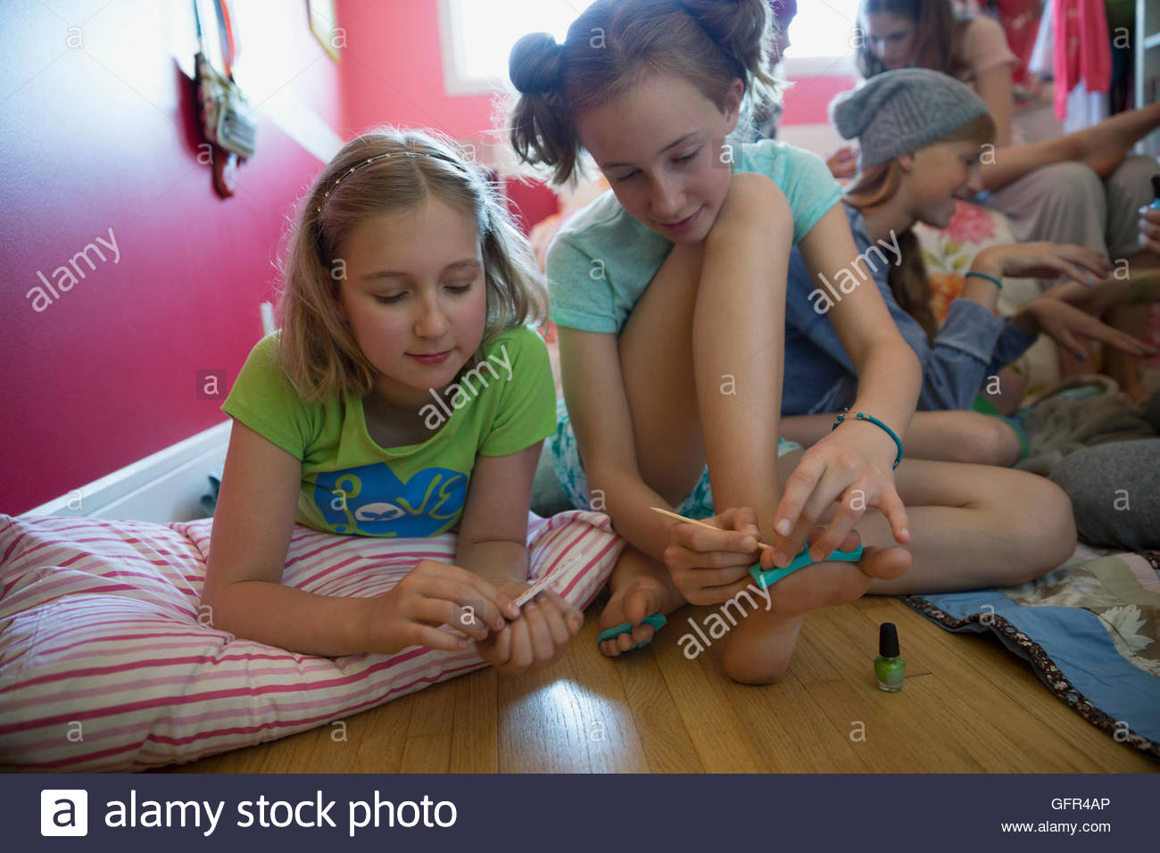 Girls filing and painting nails at slumber party Stock Photo