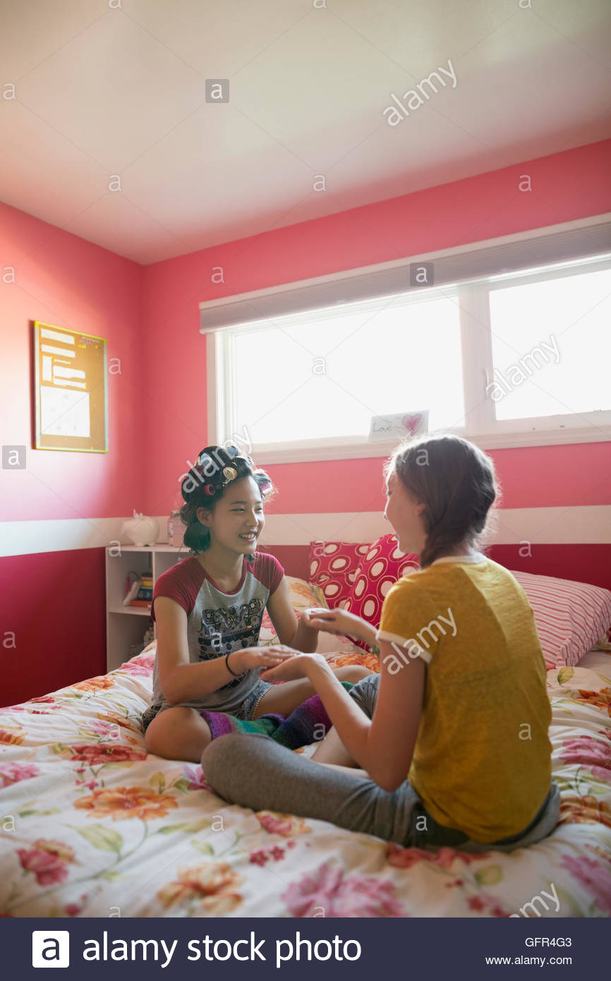Girls playing clapping game on bed Stock Photo