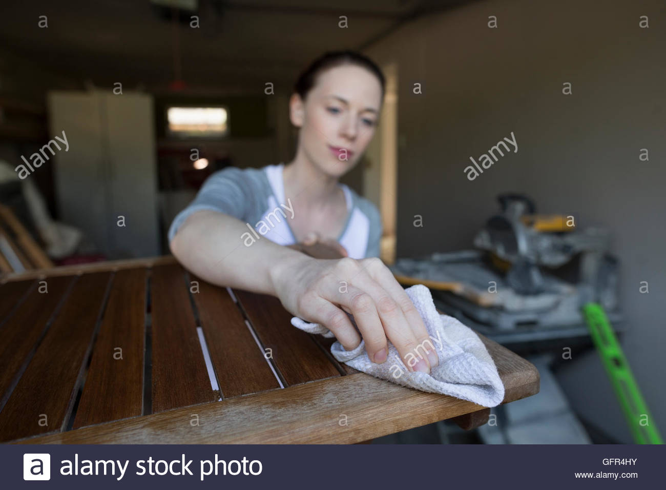 Woman staining wood furniture home improvement project in garage Stock