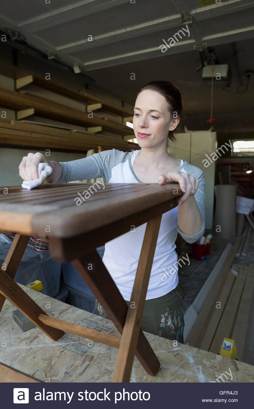 Woman staining wood furniture home improvement project in garage Stock