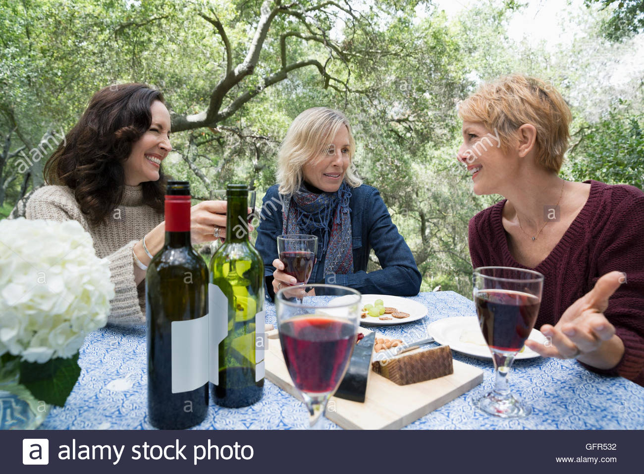 Mature women talking and drinking wine at patio table Stock Photo