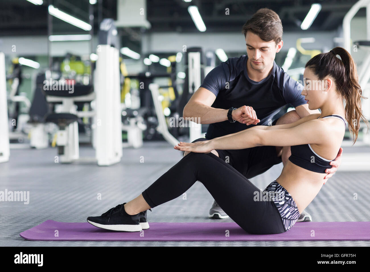 Young Chinese woman working with trainer at gym Stock Photo - Alamy