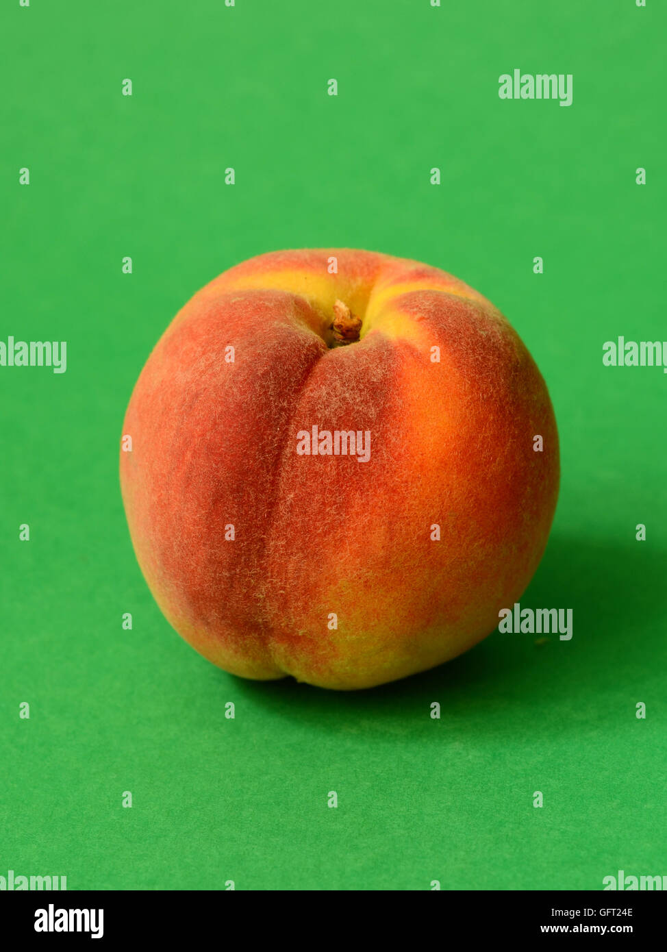 One ripe peach on a green background Stock Photo