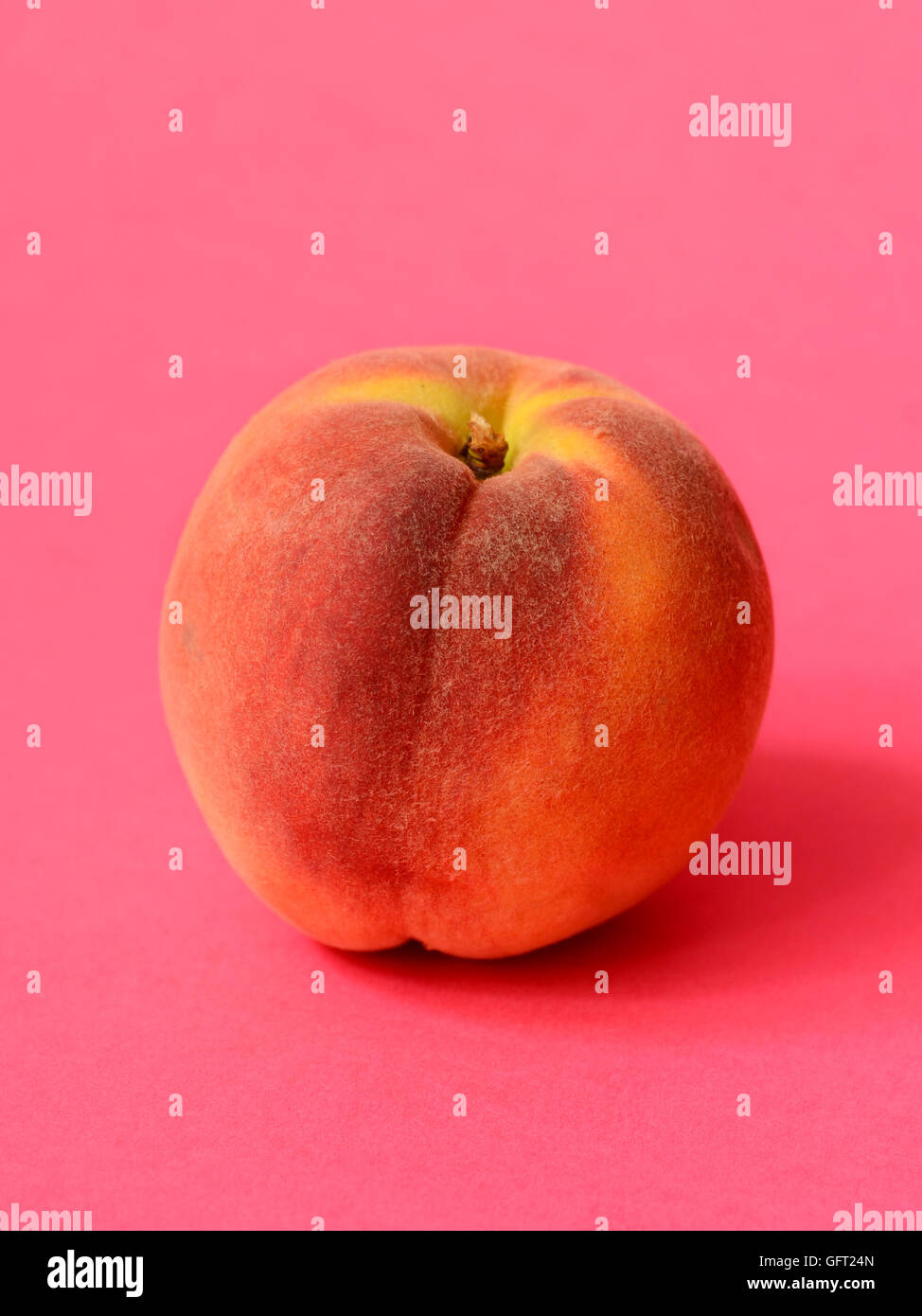One ripe peach on a pink background Stock Photo